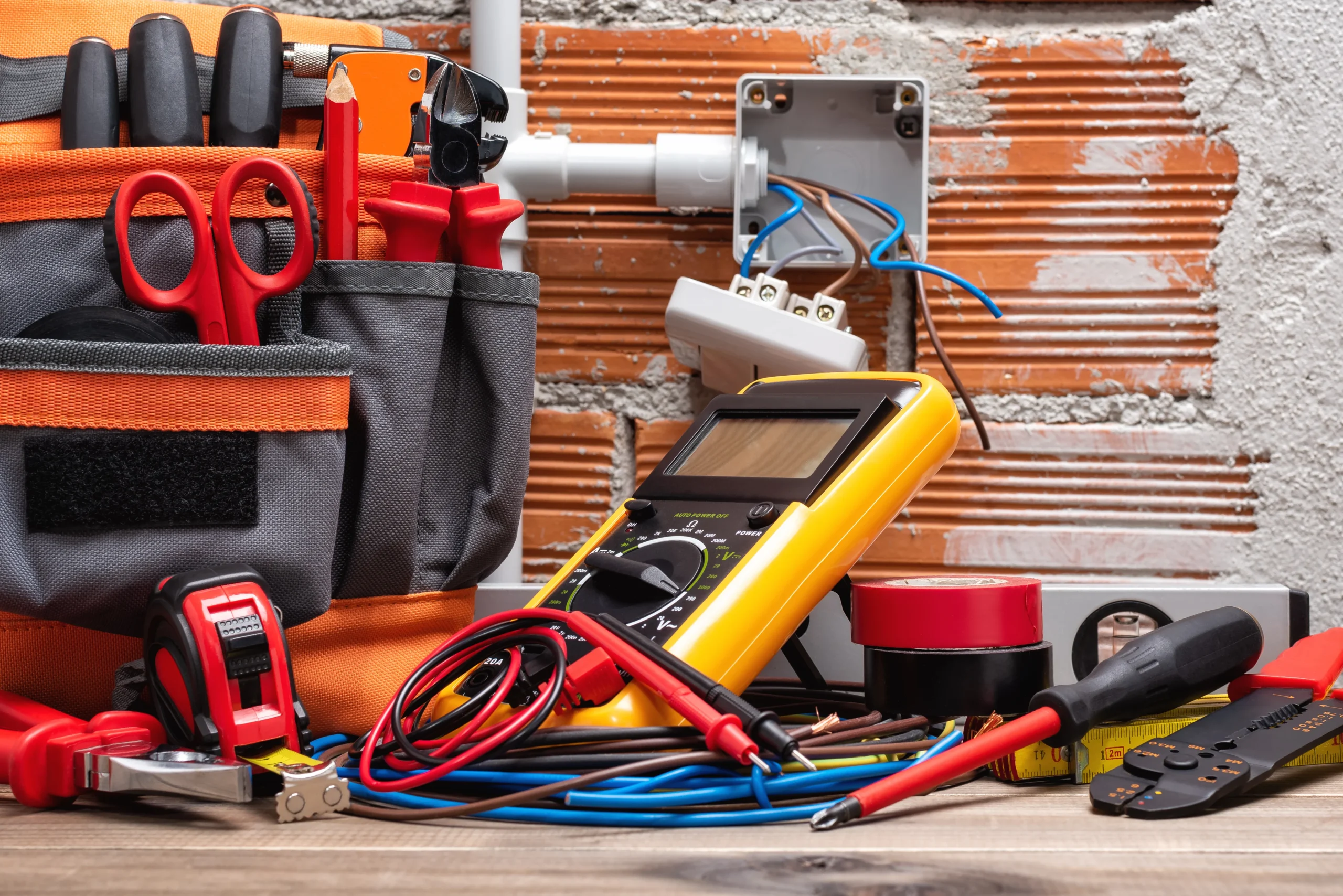 Tool bag, tools and work equipment for electrician technician on a wooden workbench. Construction industry.